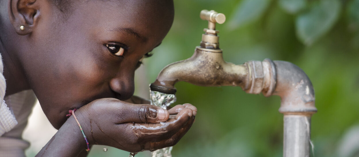Kind trinkt von öffentlichem Wasserhahn